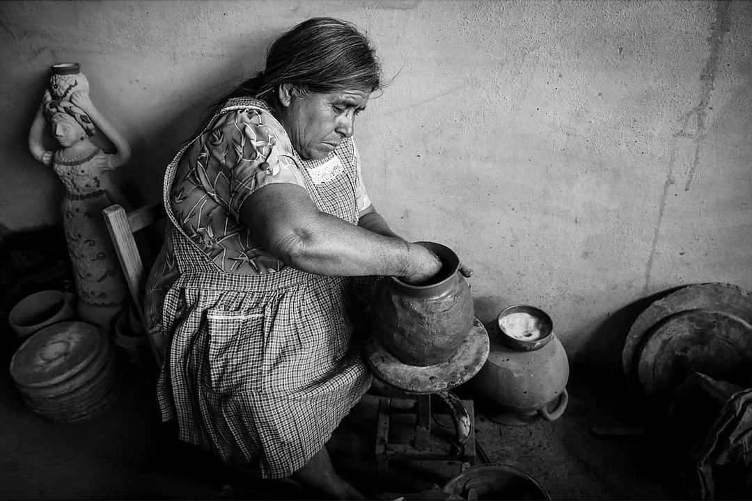 black and white, black, one person, adult, monochrome, monochrome photography, indoors, person, women, lifestyles, sitting, poverty, full length, pottery, container, darkness, working, holding