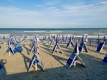 Deck chairs on beach against sky