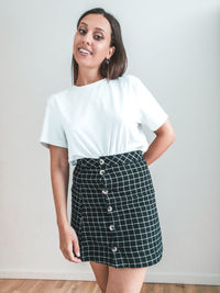 Portrait of a smiling young woman standing against wall