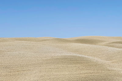 Scenic view of desert against clear blue sky