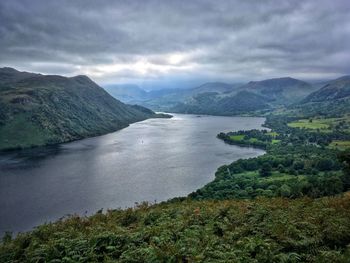 Scenic view of lake and mountains against cloudy sky