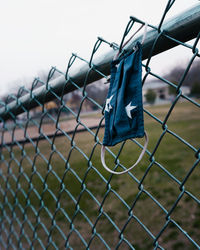 Close-up of blue facemask with white stars on chain link fence