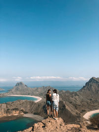 Rear view of friends standing on mountain against sky