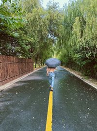 Rear view of woman walking on road