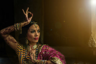 Woman in traditional clothing dancing against wall