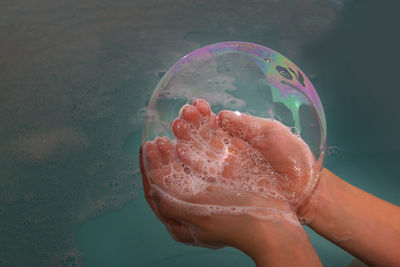 Close-up of hand holding bubbles in water