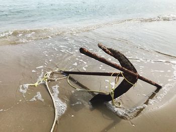 High angle view of rusty metallic anchor on shore at beach