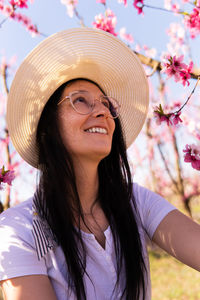 Portrait of woman wearing a hat in field of peach trees in bloom in aitona, catalonia, spain