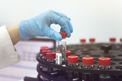 Close-up of human hand holding bottle over rack in laboratory