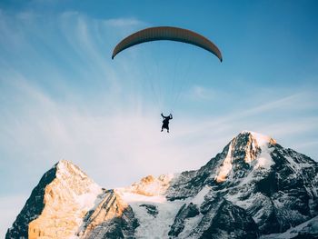 Low angle view of person paragliding against sky