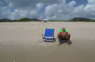 Man with umbrella on beach against sky