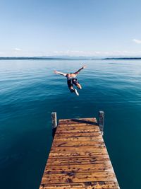 Shirtless man diving into sea against sky