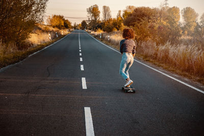 Rear view of man riding motorcycle on road