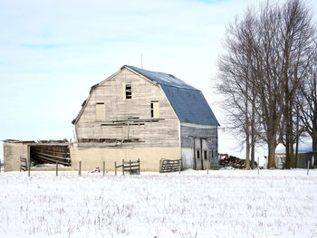 Barn on field by building against sky during winter
