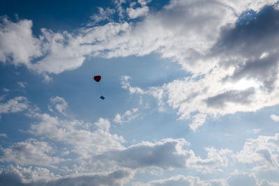 Low angle view of heart shape balloon against cloudy sky