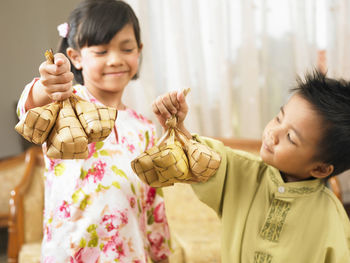 Close-up of siblings holding wicker decorations at home