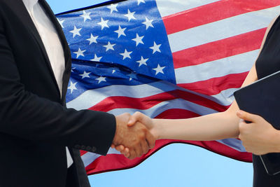 Low angle view of hands flag against blue sky