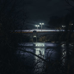 Illuminated bridge over river against sky at night