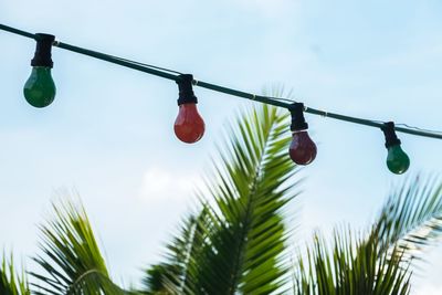 Low angle view of lighting equipment by palm tree against sky