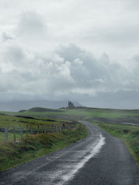 Road amidst field against sky