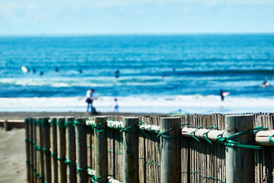 Wooden fence on beach against sky