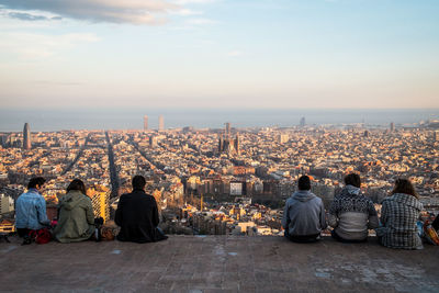 Rear view of people looking at cityscape against sky