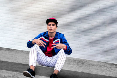 A teenage boy agains white brick wall. a male teenager model wearing casual clothing. 