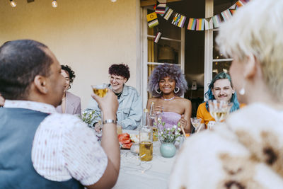 Smiling friends of lgbtq community enjoying wine during dinner party in back yard