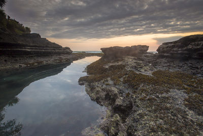 Rock formation on sea against sky during sunset