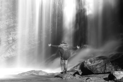 Midsection of woman with arms raised against trees