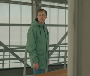 Portrait of young man standing against railing