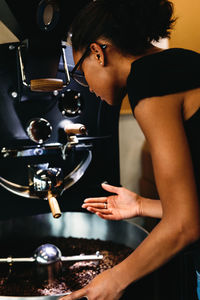 Side view of woman grinding coffee beans