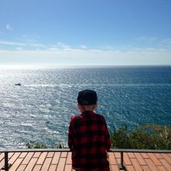 Rear view of boy looking at sea against sky