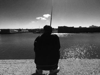 Rear view of man standing in front of sea