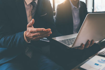 Midsection of man using laptop on table