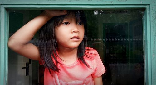 Portrait of young woman looking through window