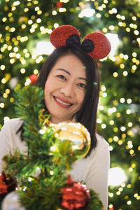 Portrait of young woman holding christmas tree