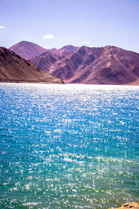 Scenic view of sea and mountains against blue sky