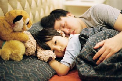 Portrait of boy with father sleeping on bed at home