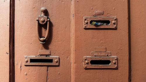 Close-up of mail slots and knocker on door