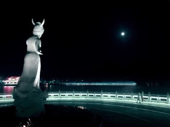 Statue against illuminated sky at night