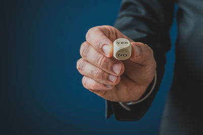 Close-up of man holding hands against blue background