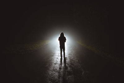 Rear view of silhouette man standing on road