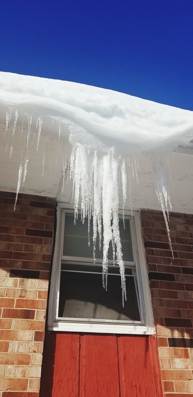 LOW ANGLE VIEW OF ICICLES ON ROOF OF BUILDING