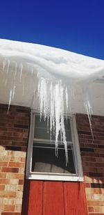 Low angle view of icicles on building roof against sky