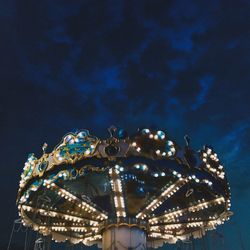 Low angle view of illuminated carousel against sky at night