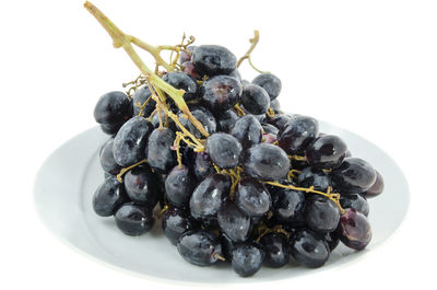 Close-up of grapes in plate against white background