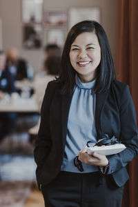 Portrait of happy female entrepreneur with diary in corporate office