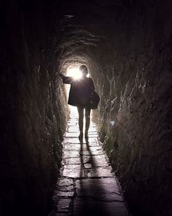 Rear view of silhouette man walking in tunnel