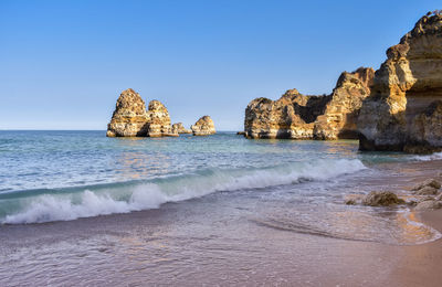 Cliffs of pinhao beach. view from below of the waves and empty sand at sunset. algarve, portugal